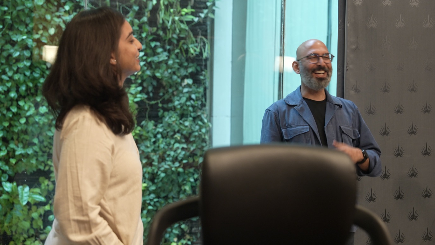Two participants standing face to face by the green wall.