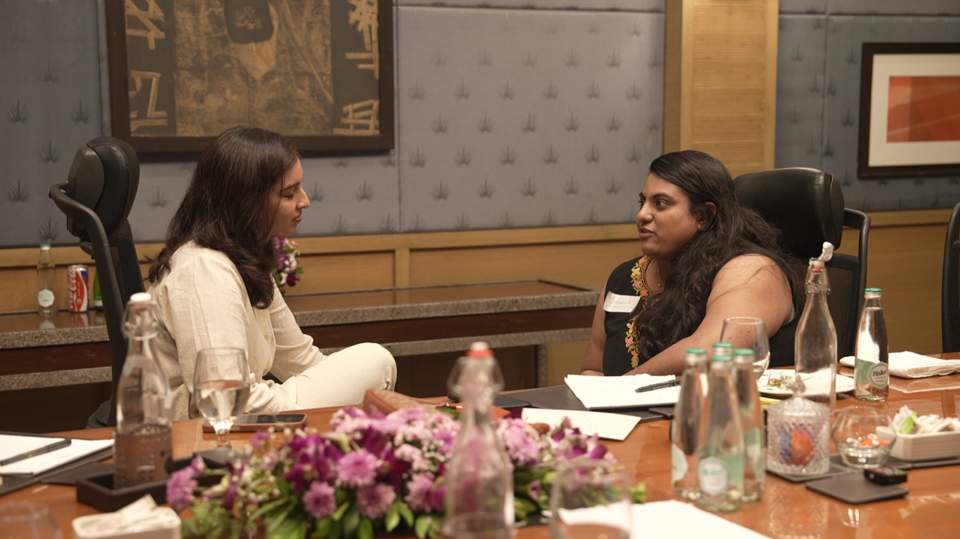 Two participants in a quiet conversation across the table.