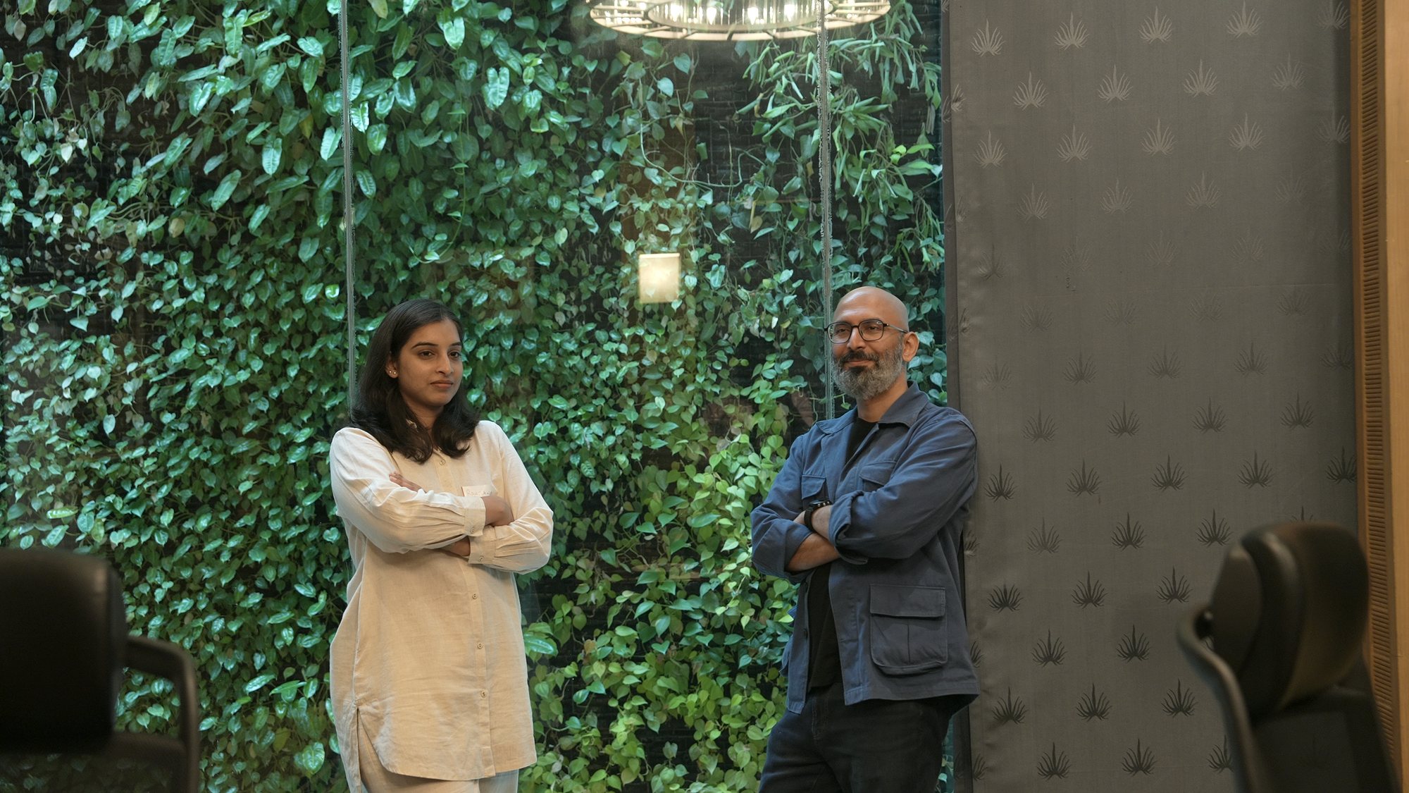 Two participants standing by the green living wall.