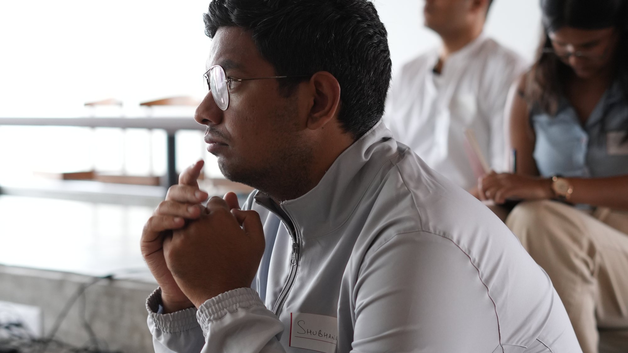 A participant listening, hands clasped, during the debrief.